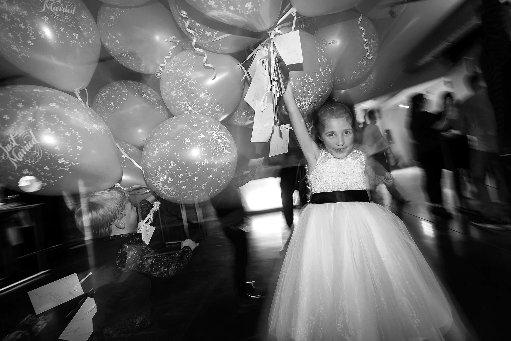 Twee kinderen dansen tussen Just Married ballonnen, motion blur
