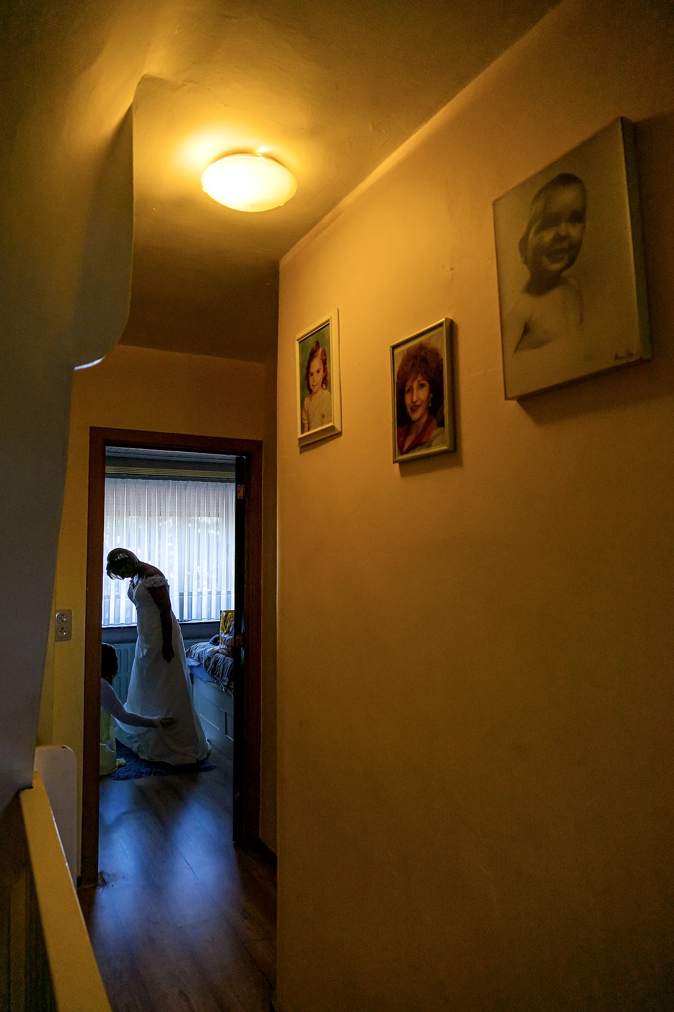 Silhouet bruid in deuropening met familieportretten