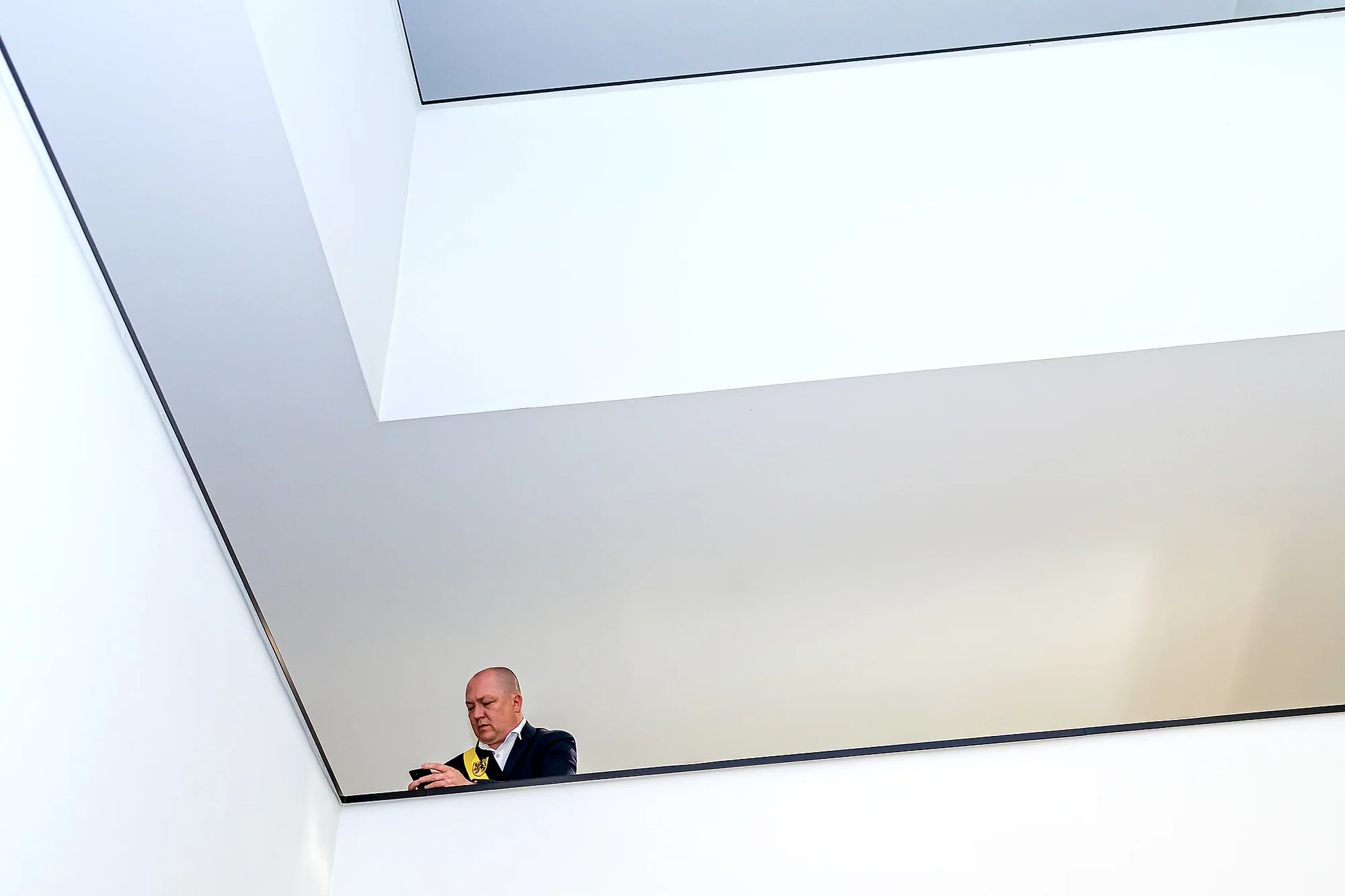 Man op telefoon in minimalistische witte sas