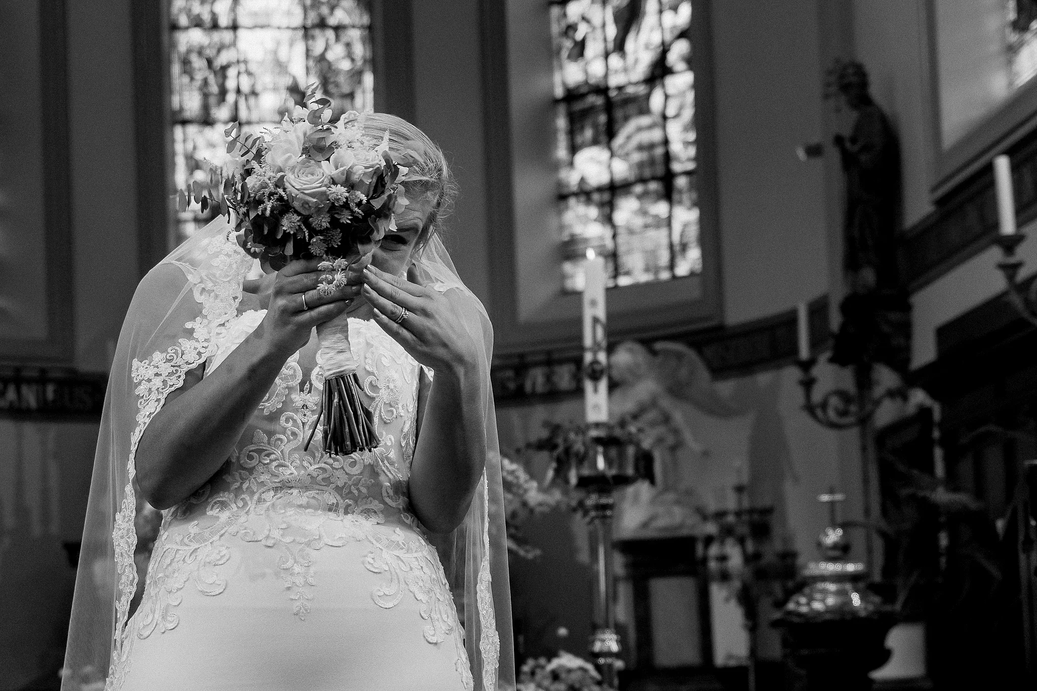 Bruid huilt achter bruidsboeket · B&W