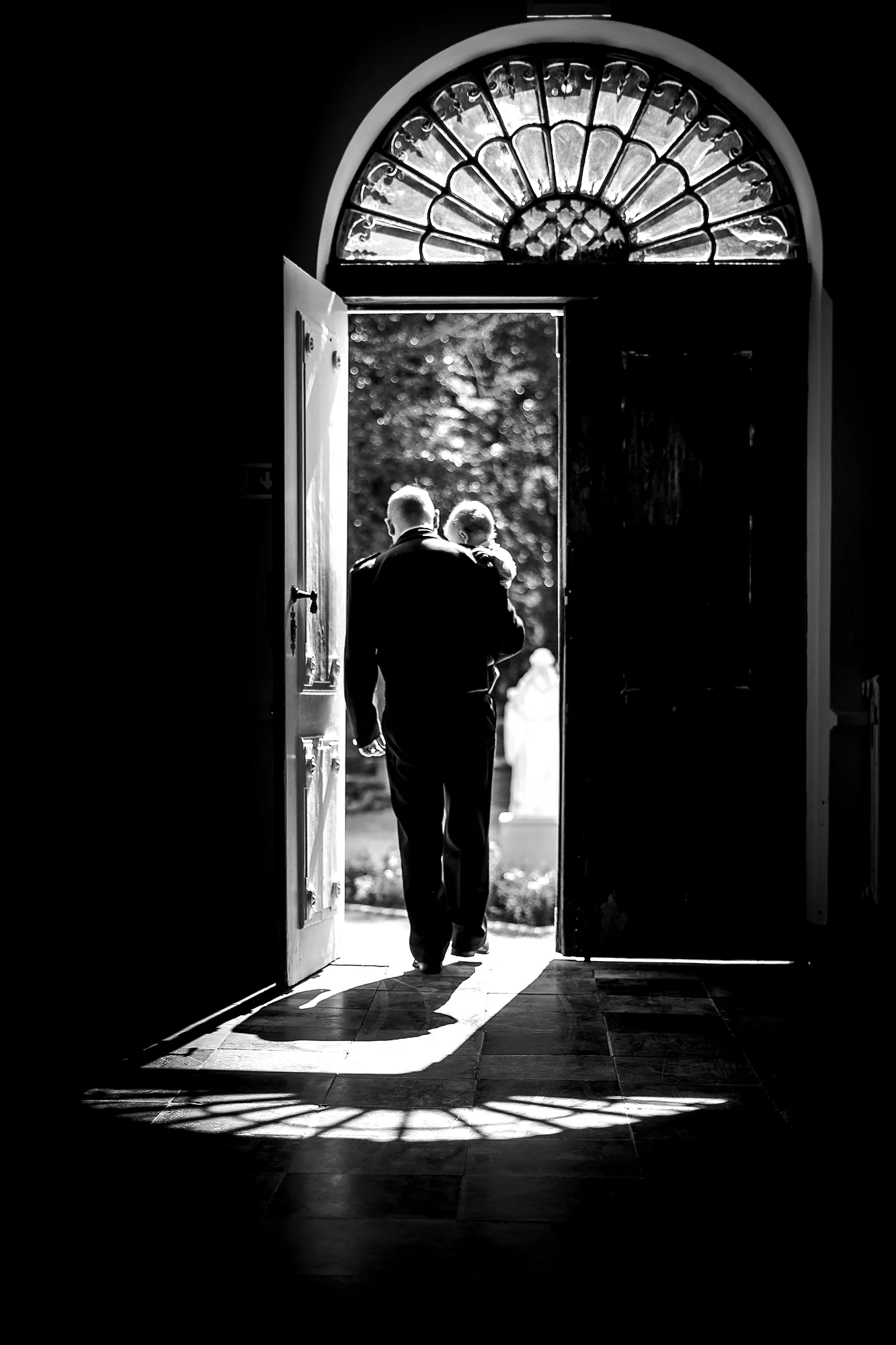 Vader draagt kind door open kerkdeur